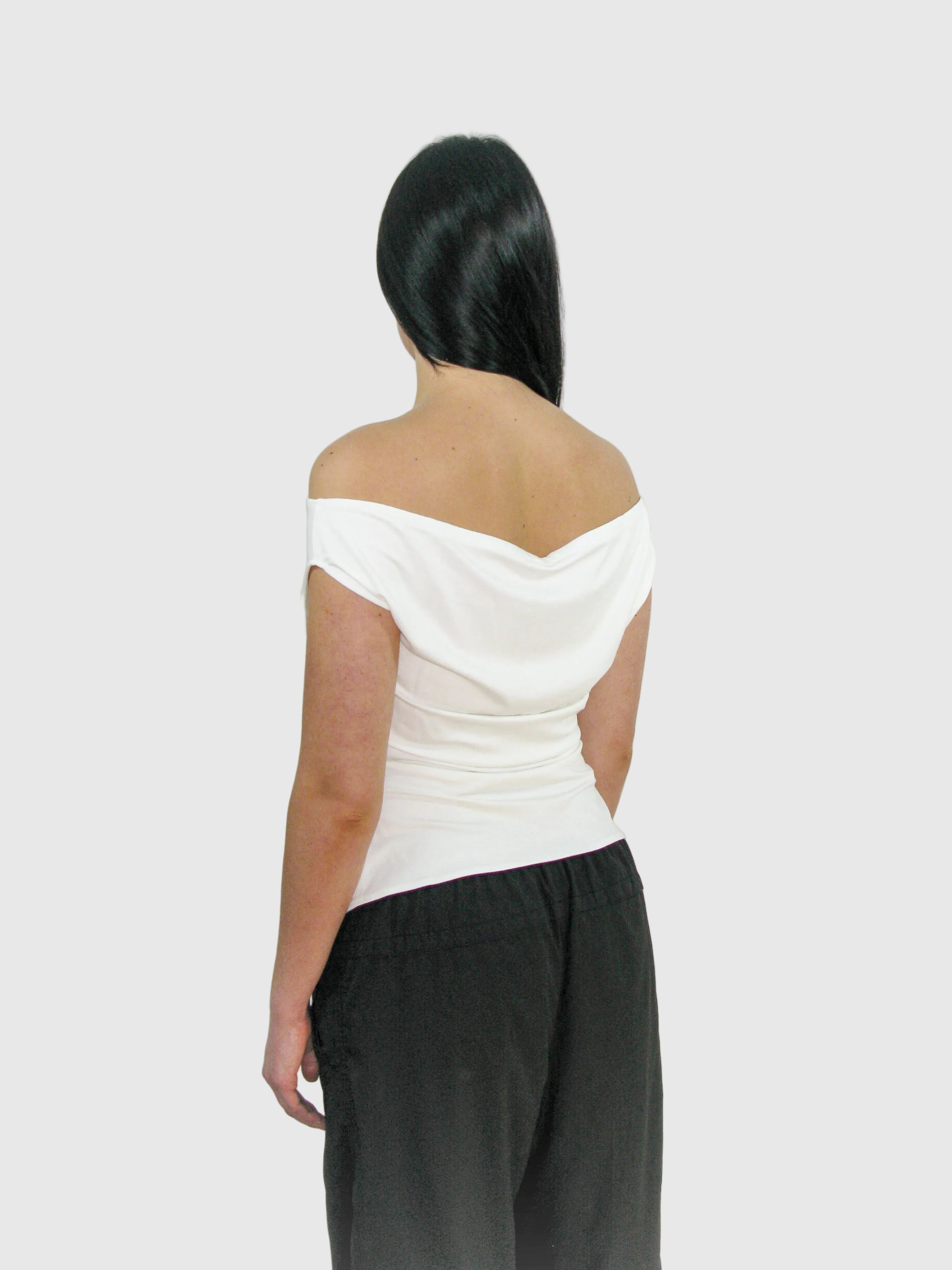 Person wearing a white off-shoulder top and black pants on a plain background