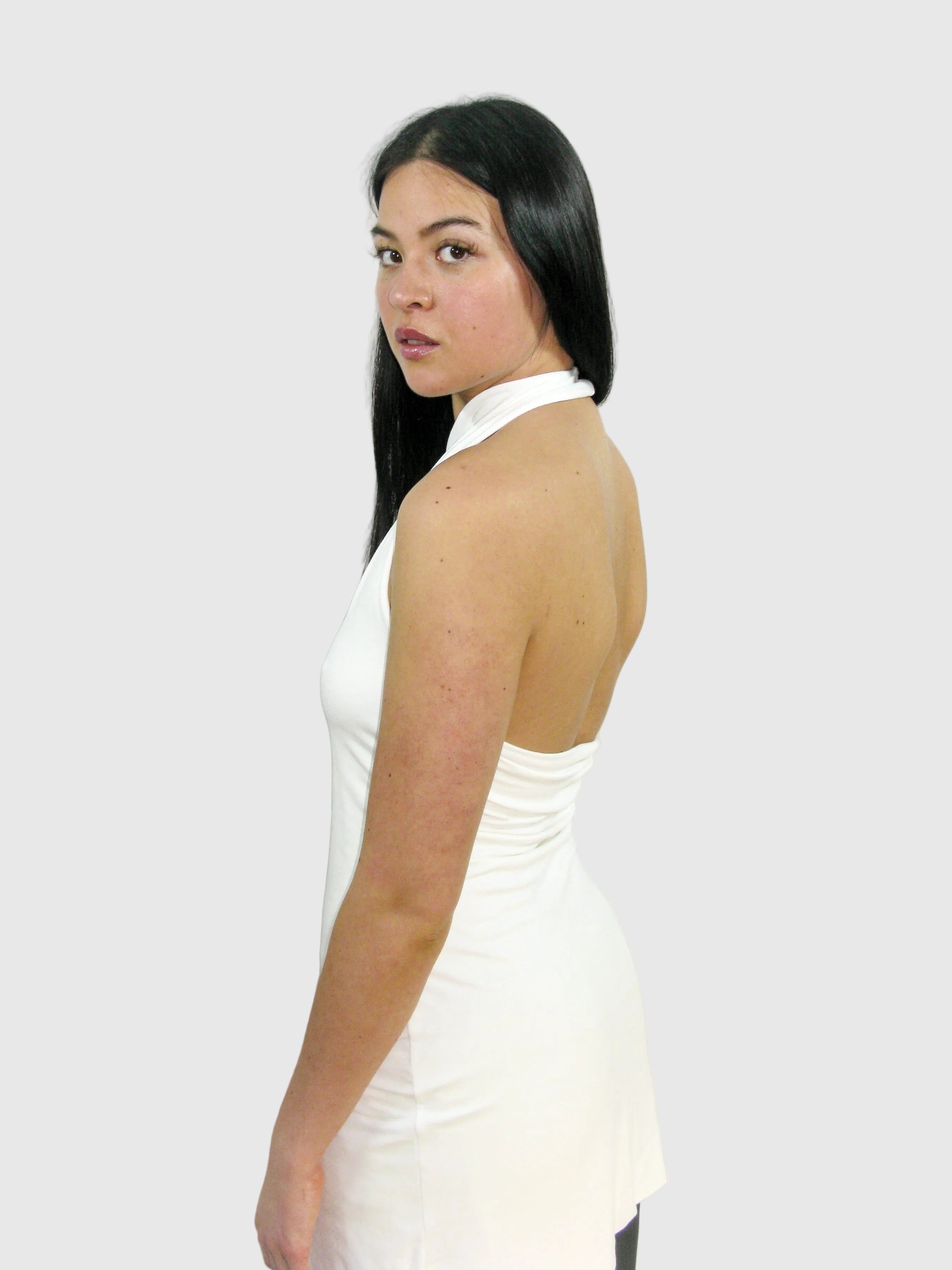 Woman wearing a white sleeveless top against a plain background