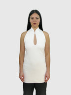 Woman wearing a white sleeveless top with a keyhole neckline against a plain background