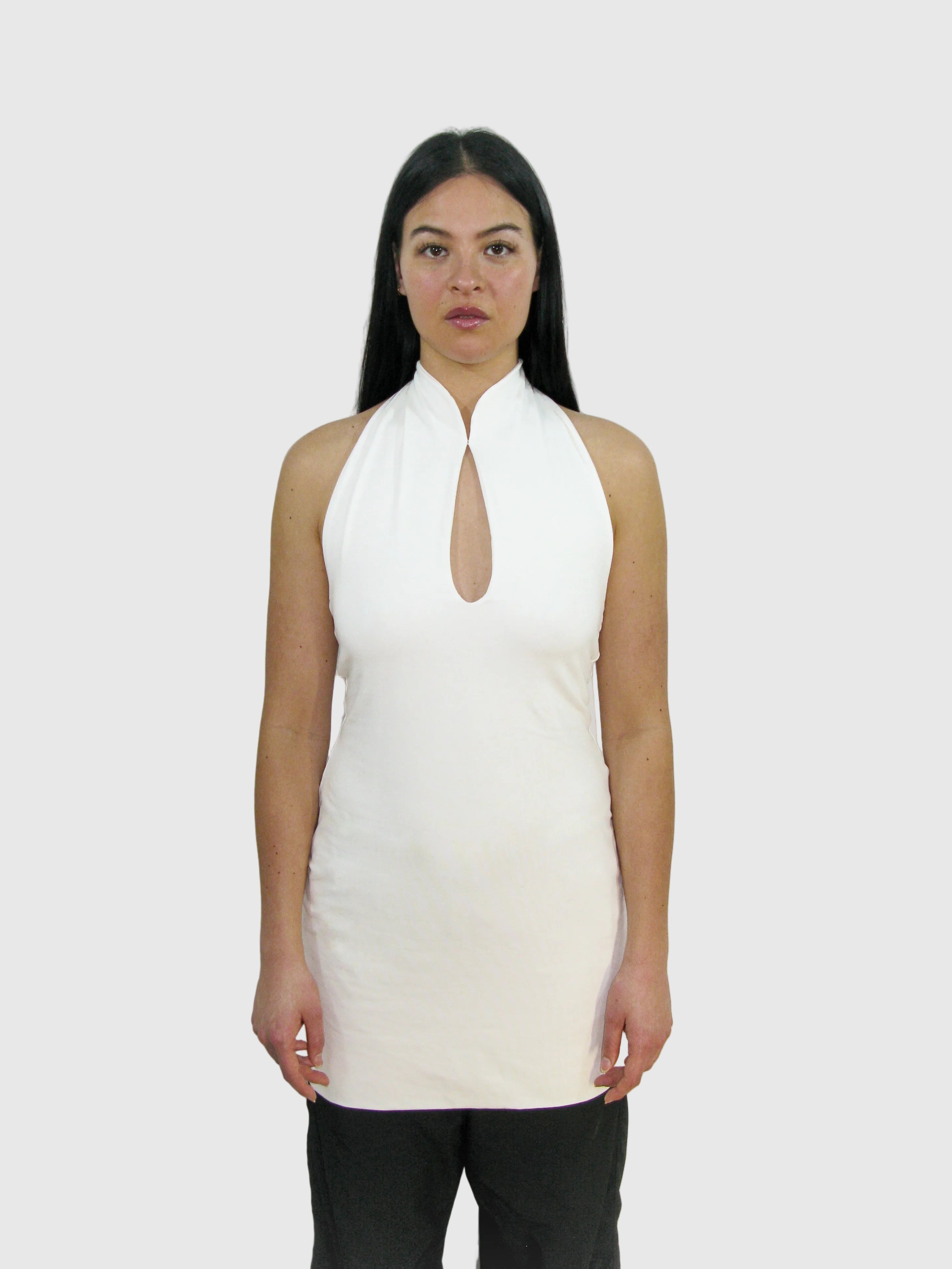 Woman wearing a white sleeveless top with a keyhole neckline against a plain background