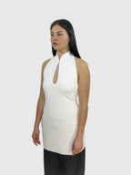 Woman wearing a white sleeveless top with a keyhole design against a plain background